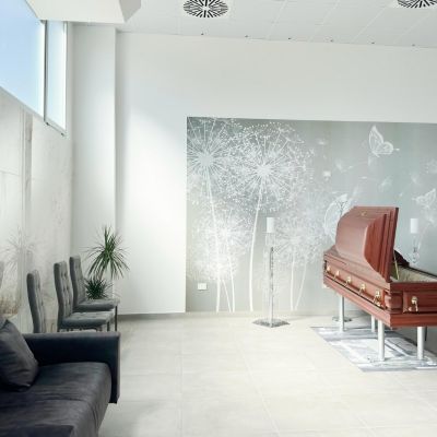 Sala del feretro luminosa con divani, sedute e decorazione floreale