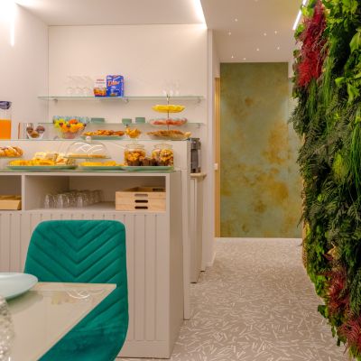 Sala colazione con tavoli, sedie e parete verde verticale
