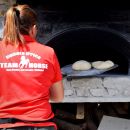 Preparazione delle pizze nel forno a legna durante una festa al maneggio