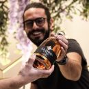 Ragazzo che porge bottiglia di genziana a altra persona Scuppoz su Instagram a Teramo in Abruzzo