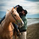 Donna abbraccia un cavallo durante una passeggiata sulla spiaggia
