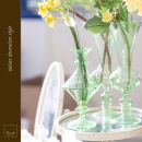 Vasi in vetro verde con fiori gialli e bianchi