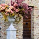 Coppa fiorita su piedistallo davanti a un muro in mattoni