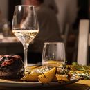 Piatto di carne con patate accompagnato da un calice di vino