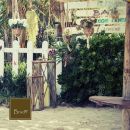 Ingresso rustico di un giardino con cancello, piante e insegna