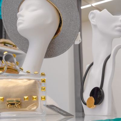 Borse e collane esposte accanto a manichini con cappello