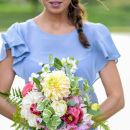 Donna con abito azzurro che regge un bouquet colorato