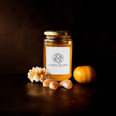 Vasetto di miele artigianale con agrumi in uno still life su sfondo scuro