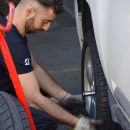 Meccanico mentre monta la ruota di un'automobile bianca