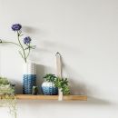Mensola con vasi blu, ceramiche e un fiore viola