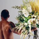 Uomo tatuato di spalle mentre regge un grande bouquet