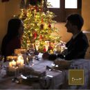 Coppia seduta a una tavola illuminata con albero di Natale
