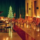 Sala per eventi con tavoli e grande albero di Natale illuminato