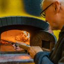 Preparazione della pizza nel forno a legna durante un evento del Maneggio Team Horse