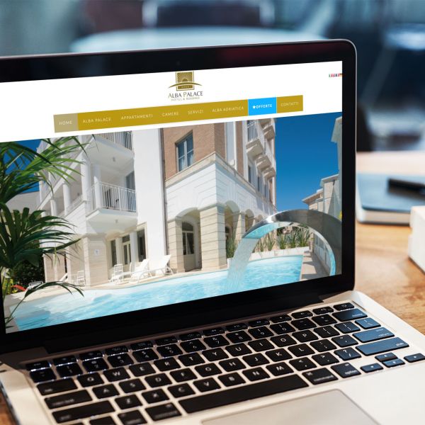 MacBook sulla scrivania con la home page del sito web di Alba Palace di Alba Adriatica