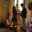 Coppia davanti all'albero di Natale mentre apre un regalo