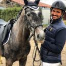 Amazzone sorridente accanto al proprio cavallo grigio