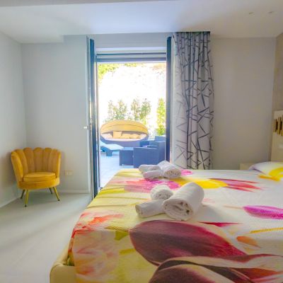 Camera della suite Tulipano con letto floreale, poltrona gialla e patio