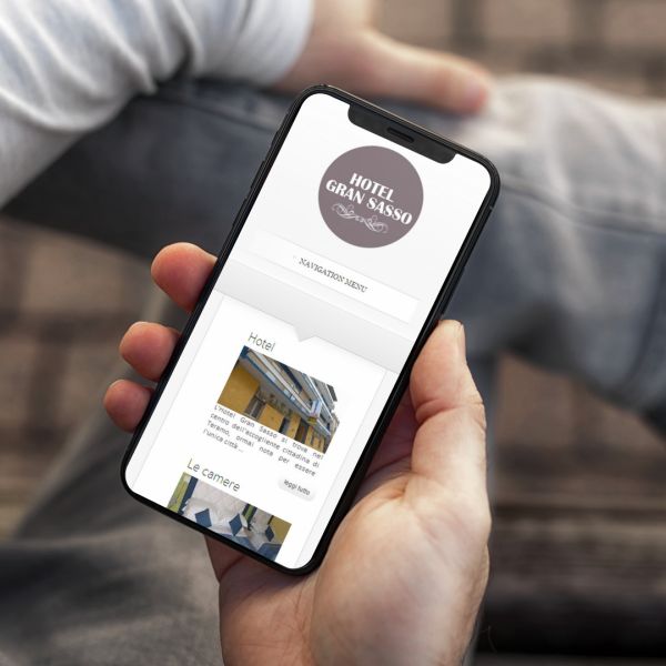 mano con Iphone che mostra il sito web in modalità mobile responsive di Hotel Gran Sasso Teramo
