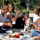 Gruppo amici picnic sorridono bevendo genziana