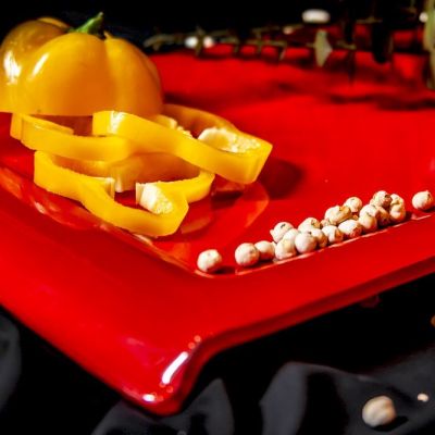 Piatto quadrato in vetro rosso con peperone giallo e grani