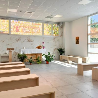 Sala del commiato con panche, fiori e vetrata artistica