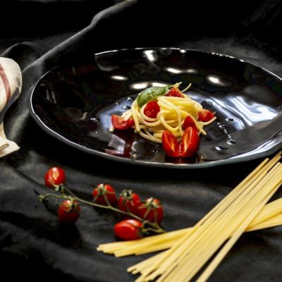 Piatto rotondo in vetro nero con peperoni colorati