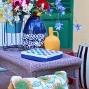 Tavola apparecchiata con bouquet colorato, cuscini e ceramiche