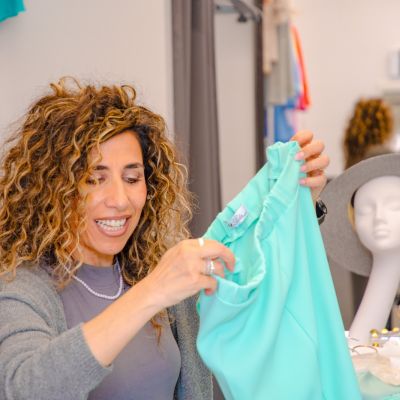 Donna sorridente mostra un capo turchese nel negozio