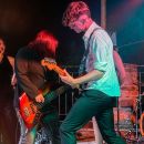 Bassista e chitarrista durante l'esibizione sotto le luci rosse