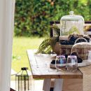 Tavola all'aperto con cesto, bicchieri e complementi naturali