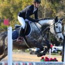 Amazzone con cavallo grigio ripresa da vicino durante un salto