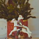 Babbo Natale su cavallo a dondolo sotto un piccolo abete