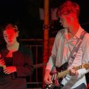 Cantante e chitarrista durante un brano sotto le luci rosse