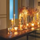 Consolle illuminata da candele con foglie e rami autunnali