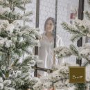 Donna visibile dietro un albero di Natale innevato