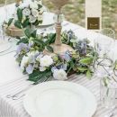 Tavola elegante con ortensie, piatti bianchi e candelabro