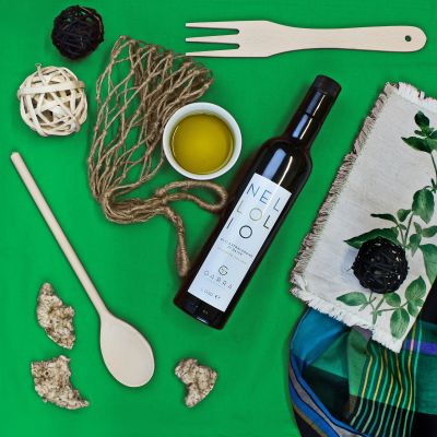Bottiglia di olio extravergine d'oliva abruzzese su set verde con ciotola d'olio