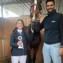 Giovane allieva con coccarda accanto all'istruttore e al cavallo nel maneggio