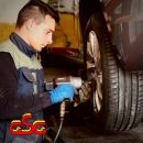 Meccanico mentre utilizza un avvitatore sulla ruota di un'auto