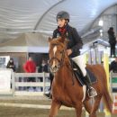 Bambina a cavallo durante una prova nel campo coperto