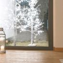 Albero decorativo bianco illuminato davanti a una vetrina