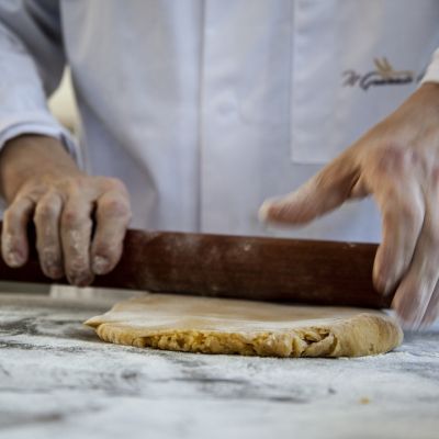 Pasticcere mentre stende l'impasto con il mattarello