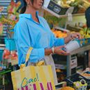Donna al mercato mentre regge una borsa colorata