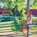 Donna in un giardino accanto a una grande pianta tropicale