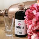 Bottiglia di Ratafia Scuppoz con bicchiere e fiori rosa