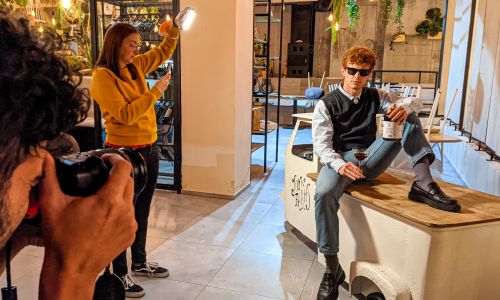 fotografi Wainet durante shooting fotografico con modello seduto con in mano prodotti Scuppoz liquori a Teramo in Abruzzo