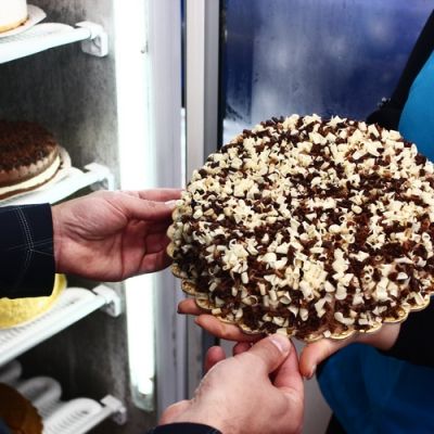 Torta al cioccolato decorata con scaglie bianche mostrata a una cliente