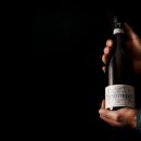 Mani che tengono la bottiglia di Montepulciano D'Abruzzo Tenuta Trium