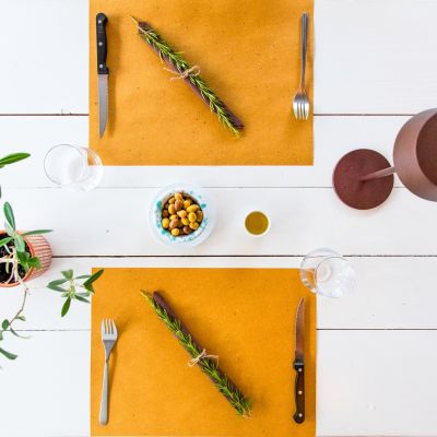 Tavola apparecchiata vista dall'alto con tovaglioli e rametti aromatici